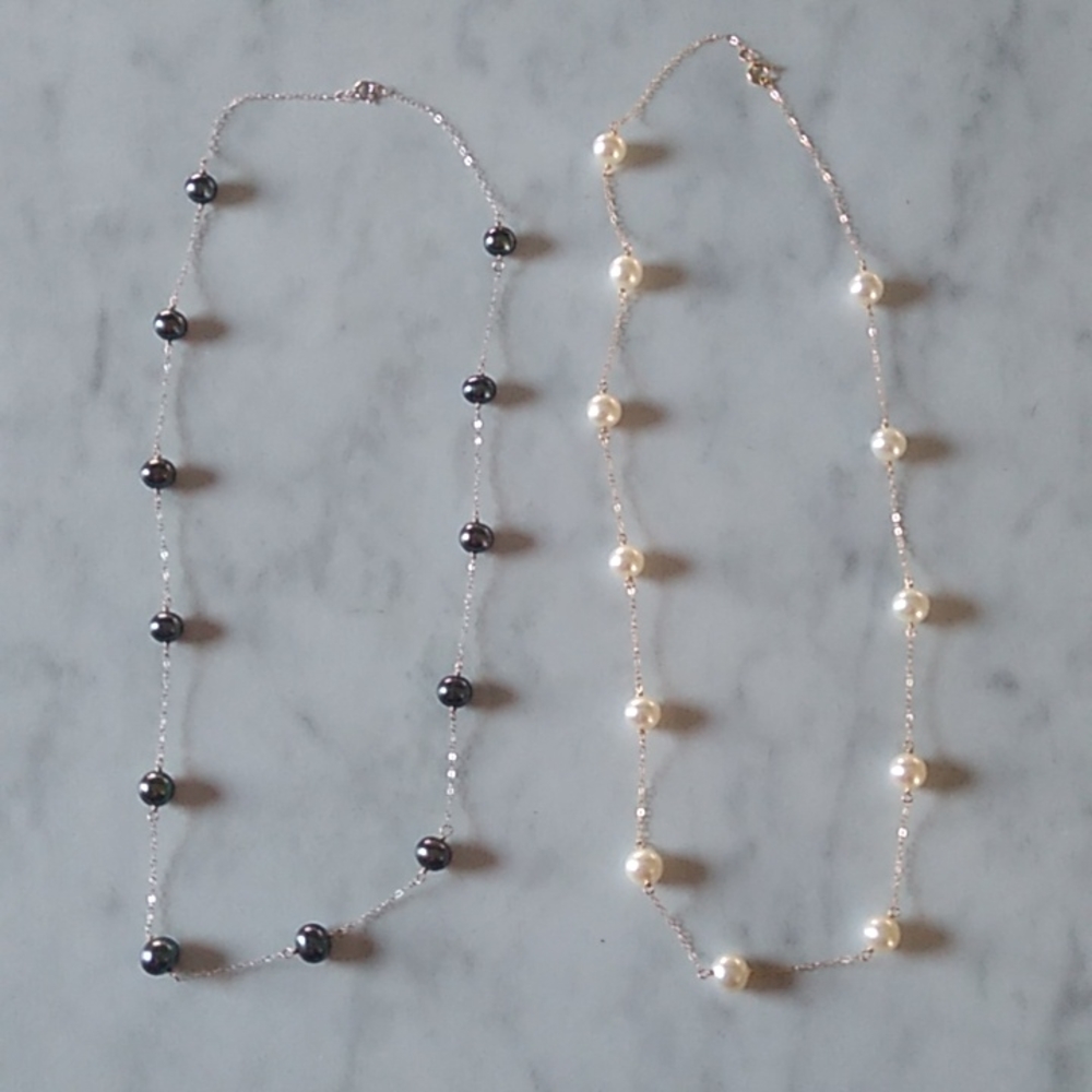Two pearl necklaces. One silver and black and the other gold and white